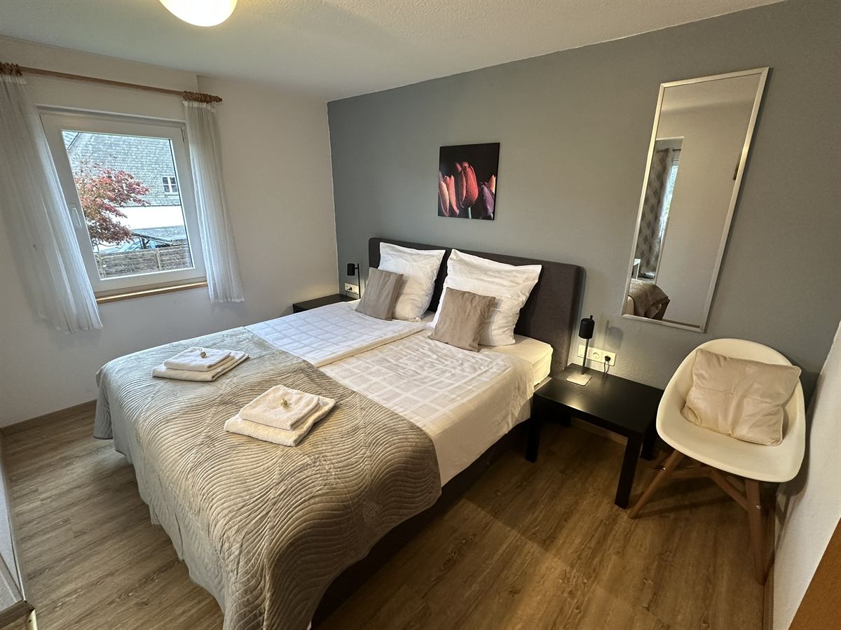 Bright room with box-spring bed and balcony at the Haus Astenalm guesthouse